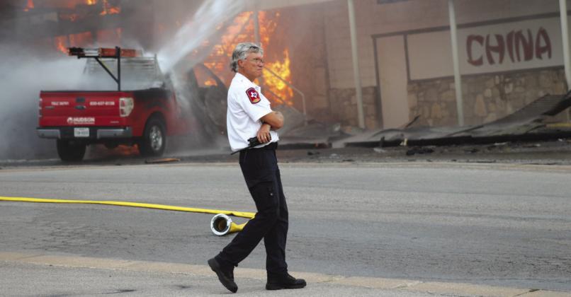 Vaughn Hamilton of Marble Falls Area EMS was on the scene, during the Oct. 4 blaze which destroyed China Kitchen building and several other businesses. A fire crew doused a Hudson Electrical vehicle in the background.