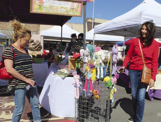 Nancy Kranz of Sunrise Beach and Angel Garrett of Meadowlakes admired several items as they browsed during Main Street Market Day in Marble Falls. The community was listed among 10 places to get away from the big city. File photo