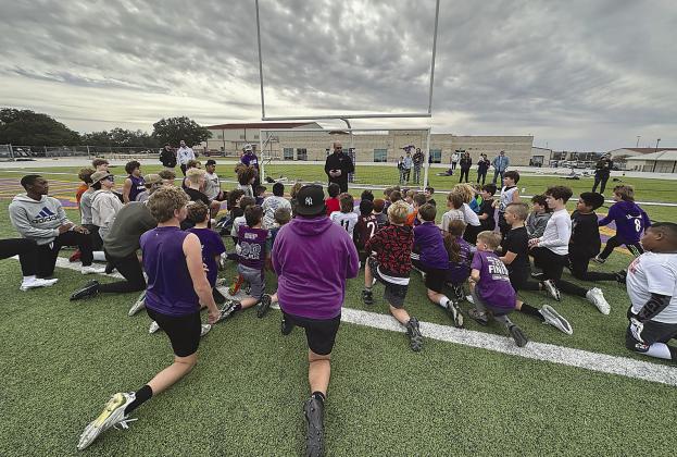 Marble Falls Independent School District athletic director and football head coach Keri Timmerman (standing, center) addresses the young football players on a recent Saturday. Contributed photo