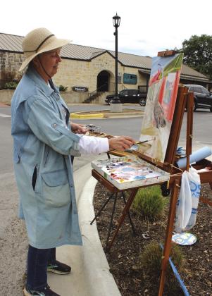 Marla Ripperda is among 35 artists participating in the Paint the Town Festival this week, hosted by Highland Lakes Creative Arts. On Monday, she painted a piece using a sculpture she created as a backdrop at the corner of Fourth and Main Street. Connie Swinney/The Highlander