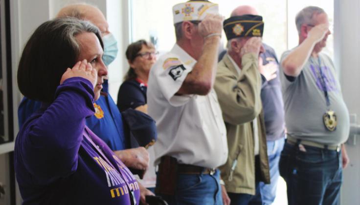 Marble Falls Veterans of Foreign Wars Post 10376 donated two flags - a US flag and an POW/MIA flag -- to Marble Falls High School for display at the veterans’ wall in the foyer. MFHS veterans, including Christina Deloach (left), received the flags and performed the ceremony. More events are planned through the rest of the week. Nathan Hendrix/ The Highlander