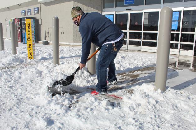Walmart employee Gary Simmerman cleared the way for shoppers Monday, Feb. 15 who made the trek into town following several inches of snow overnight. Connie Swinney/The Highlander