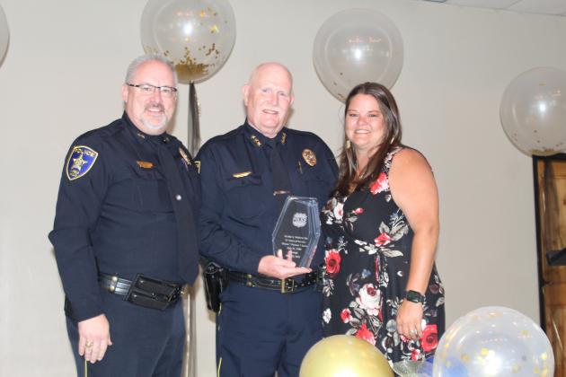 Assistant Police Chief Glenn Hanson, on the left, joined Amanda Langley on June 25, in presenting Whitacre with an award for meritorious service to the agency.
