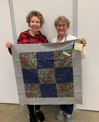 Wesley Respite Center volunteers, from left, are Lewanne Ray and Melinda Wheeler, hold a quilt gift from Healing Hearts with Helping Hands made for a participant in the program. 