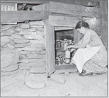 In Virginia in 1946, photographer Russell Lee took this image of Mrs. Tudor Circo, as she stored canned fruits and vegetables under a dwelling in a company housing project for the Raven Red Ash Coal Company, No. 2 Mine in Tazewell County, Virginia.