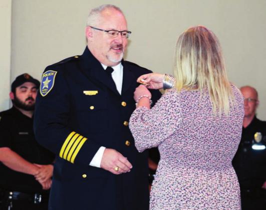 Brook Hanson ceremoniously pinned the new police chief badge on her husband Glenn Hanson June 29 during the swearing in event and reception for Glenn Hanson. Connie Swinney/The Highlander