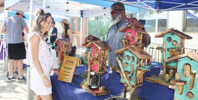 Horseshoe Bay resident Stephanie DeVault admired the custom-made birdhouses offered by Floyd Thomas during the Open Air Market June 13 in Old Oak Square in Marble Falls. Photos by Connie Swinney/The Highlander