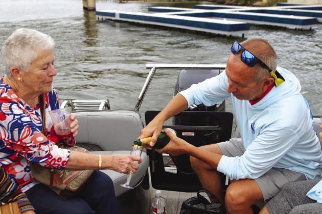 Randy Aslin pours a glass of champagne for Lorean Sindelar while being shuttled to Sand Island Oct. 11 for the Five-Flood Year Memorial.