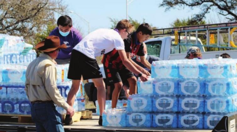 Marble Falls Independent School District students assisted county personnel, including Pct. 4 crew member Ricky Bindseil (pictured here), on Feb. 24 to organize pallets of water dropped off by troops in the stadium parking lot of Marble Falls High School. Connie Swinney/The Highlander