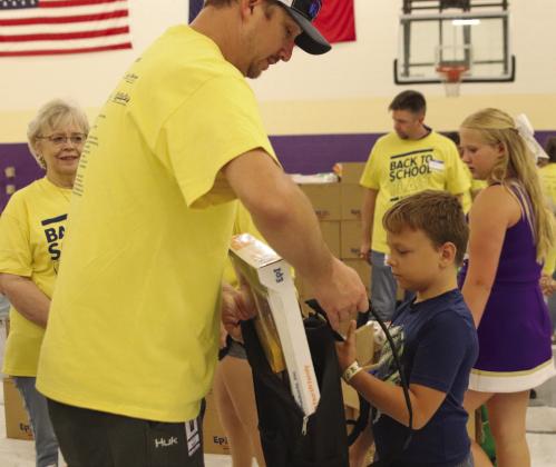 Mike Haley places backpack on Asher Johnson filled with school supplies, during the Back to School Blast Aug. 5 at Marble Falls Middle School. See more photos on Pages 2 and 3. Martelle Luedecke/Luedecke Photography