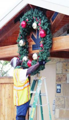 Workers, including city worker Robert Beard (above), assisted with the installation of decorations Nov. 9 on downtown amenities and US 281 light fixtures (right). Photos by Connie Swinney/The Highlander