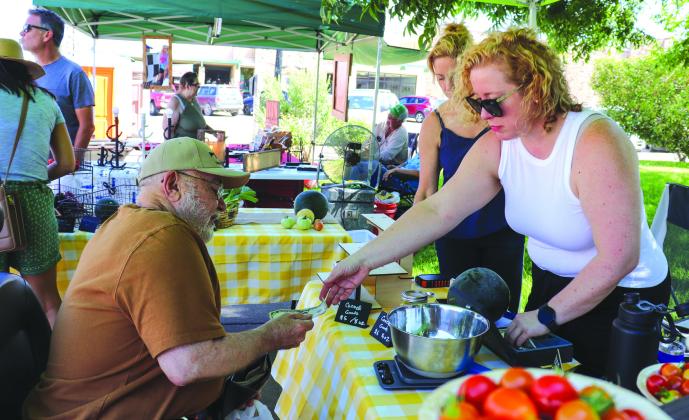 Barry Drake purchases fruits from Andrea Ames tending the Cradle Oaks Farm and Kitchen booth at the Farmers Market on the Burnet County Courthouse square. See more photos on Page 9. Martelle Luedecke/Luedecke Photography