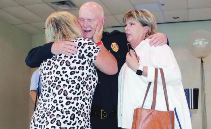 Brenda Morris, left, gives Marble Falls Police Chief Mark Whitacre a farewell gesture, while he receives a hug from Mary Jo Callaway during his retirement reception Friday. 