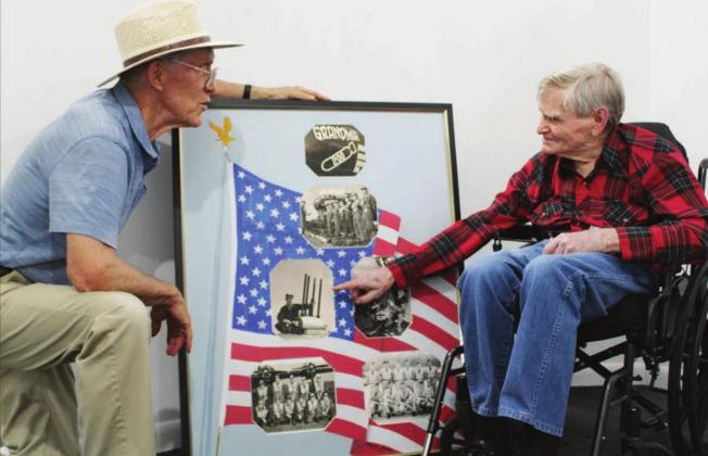 Bernie Sachs, local art gallery owner, presented a collage to veteran Robert Mead (right) on Aug. 19 at his shop on Main Street. The collage contains six photos from Mead’s time in service during the Korean War with a hand-painted background. Nathan Hendrix/The Highlander