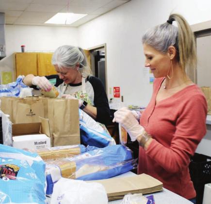 Sarah Frerking joins Mission Marble Falls Board Member Jennifer Parsons Dec. 23 in preparing sack lunches which serve as additional meals for families to take home after receiving their hot Christmas meal. Connie Swinney/The Highlander