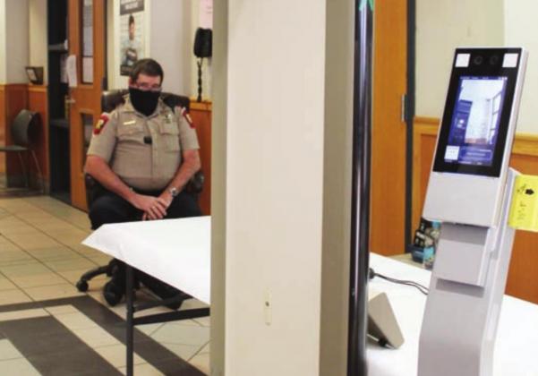 Burnet County Sheriff’s Office Deputy Jim Prew, seen here on Jan. 26, is among law enforcement on shifts who monitor a kiosk that records whether a visitor is wearing a face covering and takes temperatures at the courthouse south annex doorway. Connie Swinney/The Highlander