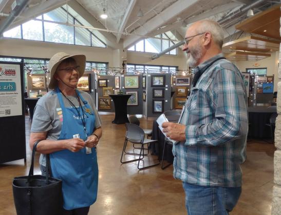 Marla Ripperda, a well-known local contributor to the annual Paint the Town, took a minute from hanging framed pictures to chat with Garland Swinney, an oil painter from Splendora. Beverly Walker/The Highlander