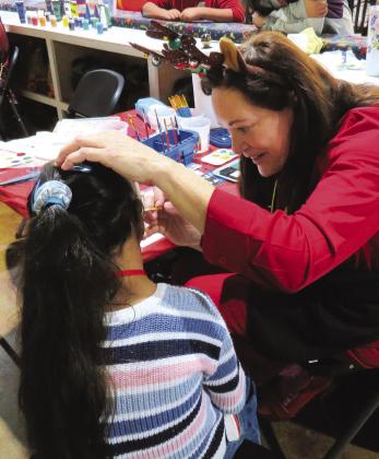 Sara Bouchard of the Highland Lakes Service League takes joy in creating a holiday face painting image for one of the participants in the Special Needs Christmas Party held at Putters and Gutters in Marble Falls. See more photos on Page 2. Contributed photo