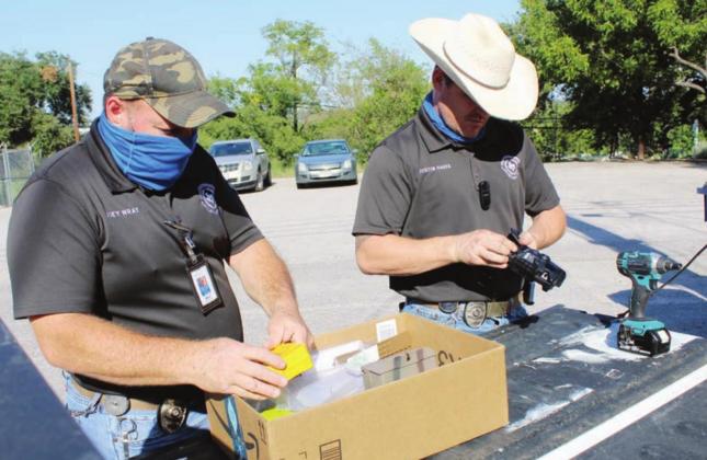 Code Enforcement Officers Joey Wray and Justin Hakes prepared to install game cameras to catch still images of people dumping illegally in city right-of-way such as alleys behind Main Street businesses. Connie Swinney/The Highlander