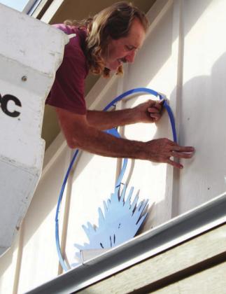 John Davis installs the iconic century plant logo of The Highlander on the front of the newspaper office at 905 Third St., Marble Falls, on Tuesday, Oct. 13. The sign was custom built by Signs2Go. Lew K. Cohn/The Highlander
