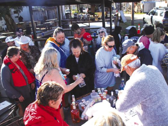 Participants gathered to imbibe the traditional tequila shot toast before plunging into the Llano River in Castell for the New Year's Day 2024 Polar Bear Plunge.