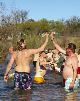 Brad Piper and Weston Ready high-five after their plunge into the Llano River at Castell for the 2024 Polar Bear Plunge.