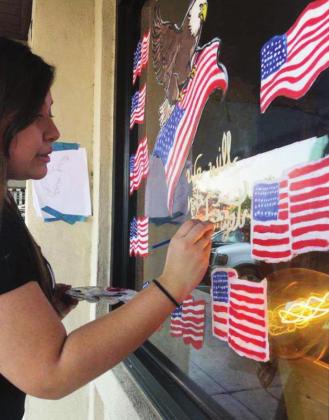 High school senior Kandy Rojas was among a handful of art classmates who designed and painted patriotic images on the window of Main Street Consignments, 216 Main St., in Marble Falls. Contributed/ Kim Thomas