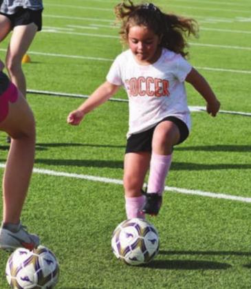 Alianna Whitley works on her dribbling skills at Monday’s soccer camp at Mustang Stadium.