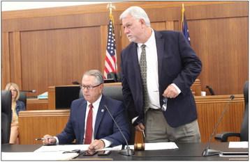 Precinct 3 Commissioner Billy Wall (standing) and Precinct 4 Commissioner Joe Don Dockery examine a land use document during the July 25 Burnet County Commissioners Court meeting. Raymond V. Whelan/The Highlander